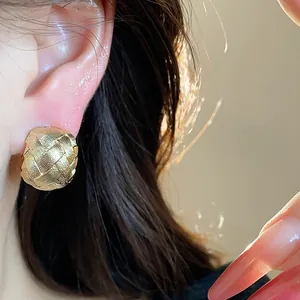 Primo piano dettagliato di orecchini a clip intrecciati placcati oro 18 carati.