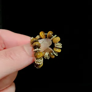 Detail view of gold-plated ear cuff featuring tiger's eye beads with chatoyancy texture