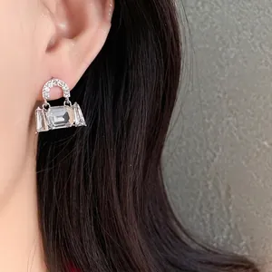 Elegant bag-shaped crystal earrings for women with silver pins, shown worn on ear