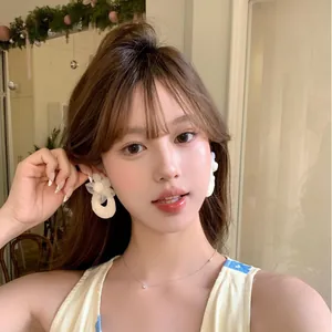 Close-up of elegant French style white flower earrings with pearl details on model.