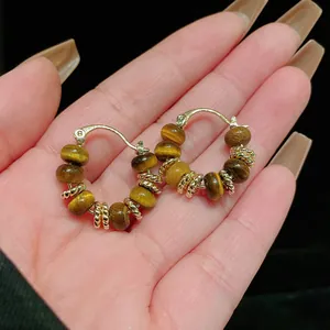 Macro view of vintage gold-plated hoop earrings featuring natural tiger eye stone beads