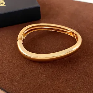 Modern minimalist irregular geometric bangle bracelet with a polished gold finish