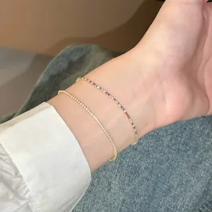 Gros plan de deux bracelets en zircon avec des pierres claires et colorées sur un poignet