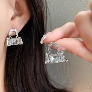 Macro detail of sparkling crystal handbag-shaped stud earrings in silver finish