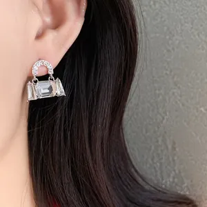 Close-up of a silver needle handbag earring with sparkling clear rhinestones