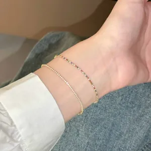 Gros plan de bracelets minimalistes en zircon et arc-en-ciel sur un poignet