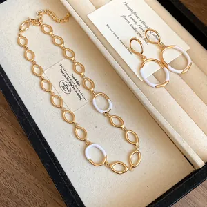 Nahaufnahme der goldenen ovalen Gliederkette mit weißen Emaille-Akzenten in Schmuckschatulle