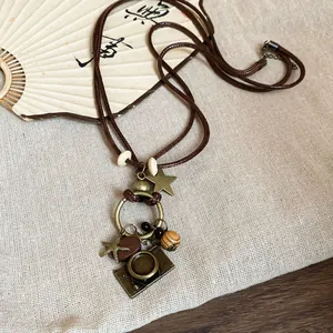 Vue détaillée d'un collier ethnique rétro avec pendentifs appareil photo et étoile