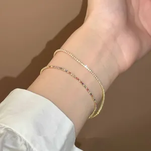 Gros plan détaillé sur un ensemble de bracelets en zircon doré et arc-en-ciel au poignet