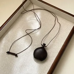 Dettaglio di una collana vintage in legno scuro su un vassoio da esposizione strutturato