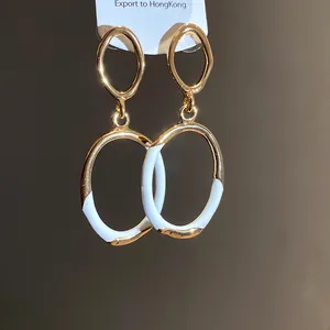 Detail von goldenen ovalen Retro-Ohrringen mit weißer Emaille und Hohl-Design.