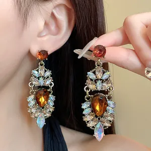 Gros plan de boucles d'oreilles vintage style cour avec cristaux ambre et irisés.
