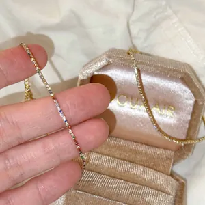 Gros plan d'un bracelet minimaliste en or avec des zircons colorés dans un écrin