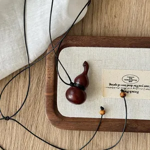 Vista dettagliata di una collana con ciondolo a zucca in legno con cordino sottile