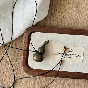 Vista dettagliata di una collana vintage con ciondolo a forma di zucca in legno su vassoio