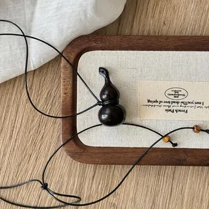 Vista dettagliata di una collana con ciondolo a zucca in legno scuro su vassoio