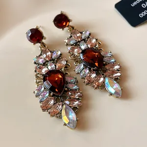 Détail de longues boucles d'oreilles style cour vintage avec cristaux rouges et irisés