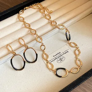 Nahaufnahme einer goldfarbenen Halskette und Ohrringen mit schwarzem Emaille-Detail