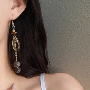 Close-up of vintage ethnic style dangling earring with irregular wood and gold hollow circle