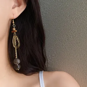 Detailed close-up of irregular wood and metal ethnic vintage drop earrings on a model