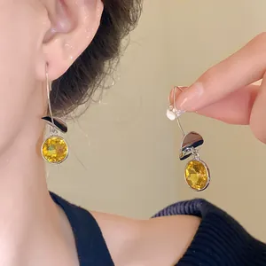 Primo piano di orecchini d'argento con cristalli gialli e ciondoli chic