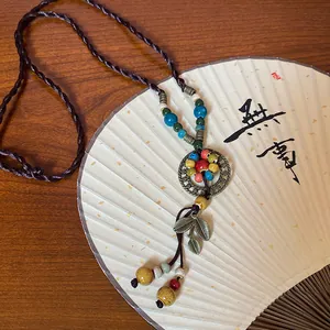 Détail du collier de style ethnique avec perles en céramique et pendentif feuille