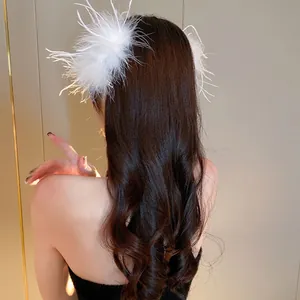 Elegant fluffy white ostrich feather hair claw clip accessory shown in wavy brown hair