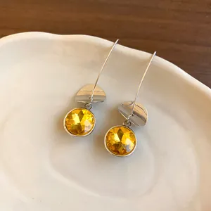 Dettaglio di orecchini vintage in argento con cristalli gialli su piatto di ceramica