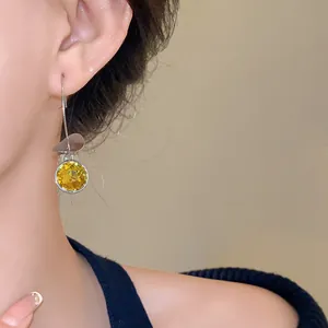 Primo piano di una modella che indossa eleganti orecchini in cristallo giallo e argento