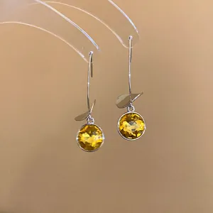 Dettaglio ravvicinato di eleganti orecchini argentati con vibranti pietre gialle sfaccettate