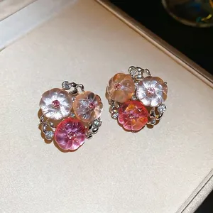 Nahaufnahme von zarten Blumenohrringen mit durchscheinenden Harzblüten und rosa Strasssteinen
