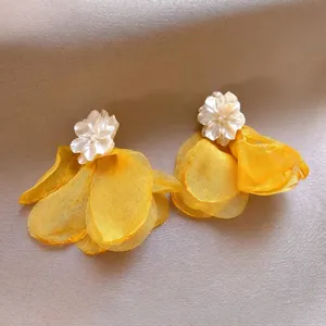 Macro detail showing texture of yellow mesh rose earrings with cream petal studs