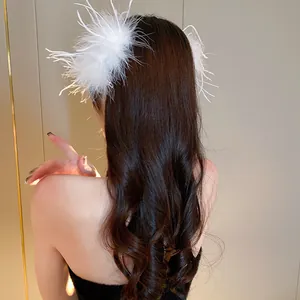 Detail view of a white ostrich feather hair clip worn on long wavy brown hair