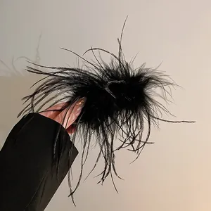 Detailed macro shot of an elegant black ostrich feather hair claw clip with fluffy texture.