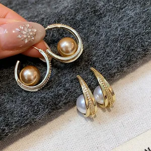 Primo piano di orecchini a cerchio dorati in stile francese con perle champagne e zirconi