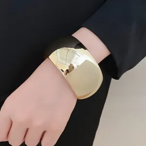Close-up of a wide acrylic geometric bangle with a glossy gold and black finish