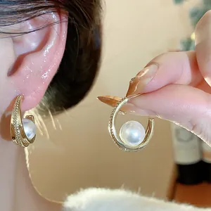 Dettaglio ravvicinato di eleganti orecchini dorati in stile francese con zirconi e perle