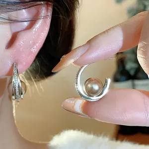 Dettaglio di orecchini a cerchio a C con perle lucenti e micro-pave di zirconi.