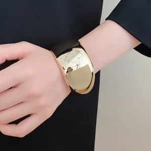 Macro detail of a chunky geometric acrylic cuff in polished gold and black finishes.