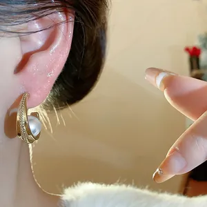 Primo piano di un orecchino vintage in oro con perla grande e zirconi brillanti