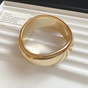 Macro view of a chunky gold acrylic geometric round bangle in a white display tray.