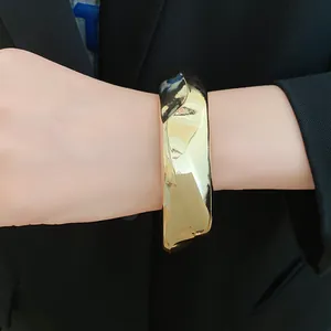 Close-up of a stylish golden acrylic faceted geometric bangle on a wrist with a black suit