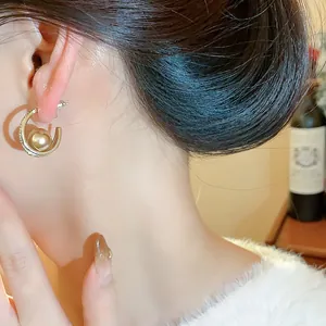 Dettaglio di orecchino a cerchio con perla e zirconi in stile francese su un modello