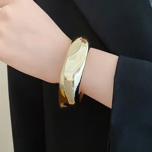 Close-up of a chunky geometric faceted gold-colored acrylic bangle bracelet