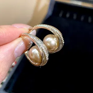 Primo piano di eleganti orecchini dorati francesi con perle e pavé di zirconi