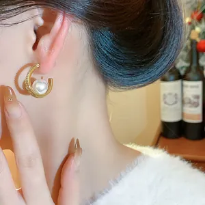Primo piano di un elegante orecchino a C dorato con perla sull'orecchio della modella