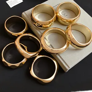 Detailed close-up showing glossy gold-finish geometric acrylic bangles on a minimalist book.