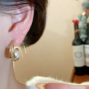 Primo piano di orecchini a cerchio con perle stile francese e zirconi indossati