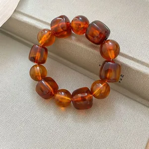 Detailed close-up of amber acrylic marbled bracelet featuring square and round beads