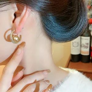 Dettaglio di un orecchino a cerchio dorato vintage francese con perla e zirconi
